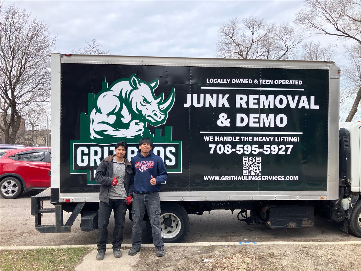 The Grit Bros Hauling founders standing in front of their branded junk removal box truck in Chicago